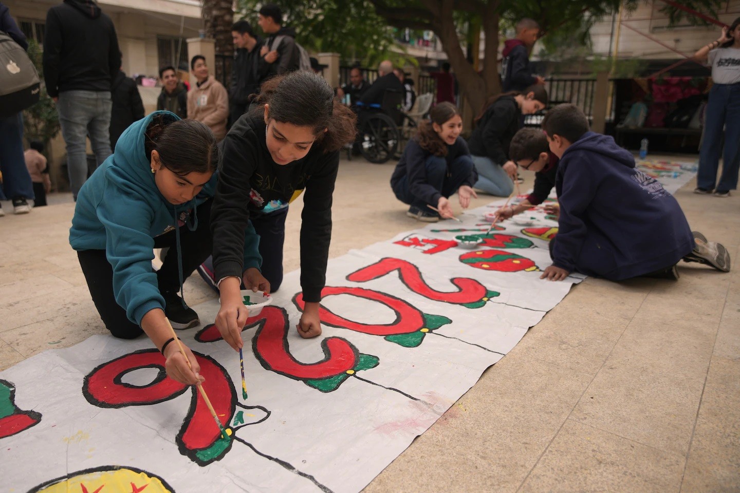 شبان فلسطينيون يرسمون لافتة عيد الميلاد في كنيسة العائلة المقدسة بمدينة غزة. (جهاد الشرفي - أسوشيتد برس)